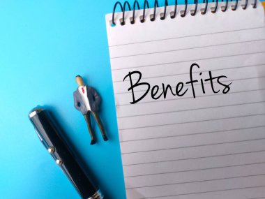 Minyatür insanların ve kalemlerin mavi arkaplandaki deftere yazılan metin faydalarının üst görüntüsü