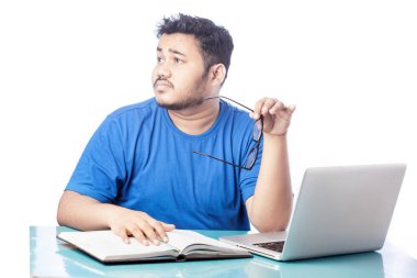 Hüsrana uğramış bir adam dizüstü bilgisayarla çalışırken kendini bitkin hisseder ve gözlük camını çıkarır.