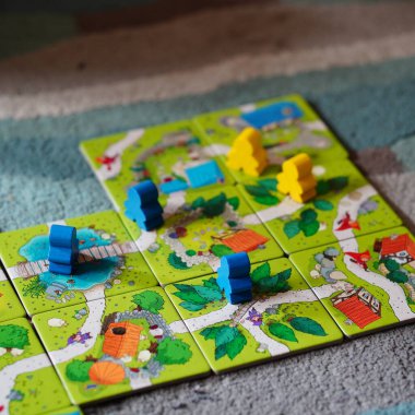 Mindok Carcassonne Junior masa oyununun kartlarından yapılmış bir haritanın üzerinde duran bir heykel.