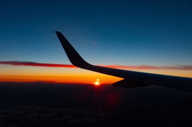 Gün batımında bir uçağın kanadının penceresinden güzel bir çekim.