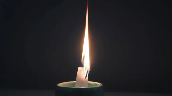 A closeup of a candle lighting up and illuminating in the darkness