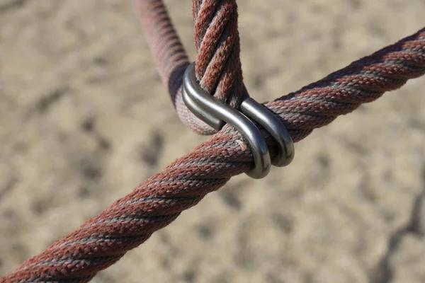 A closeup of thick red ropes tightened with metal clip