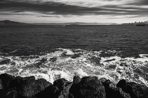 曇った空の下で波状の太平洋が砕ける岩の灰色のショット — ストック写真