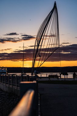 Bir göl güvertesinde yelken tasarımının bulutlu sarı günbatımı görüntüsü