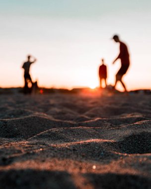 Sahilin düşük açılı kumları ve arka planda tatilin tadını çıkaran insanları bulanıklaştırıyordu.