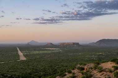 Namibya, Damaraland manzarası, büyük kayalar ve gün batımında toprak bir yol.
