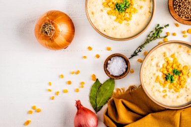 Mısır ve soğanla kaplanmış, ahşap bir masa üzerinde yemek kaselerinin üst görüntüsü.