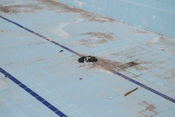 A closeup shot of a swimming pool ground without water and dirty in daylight