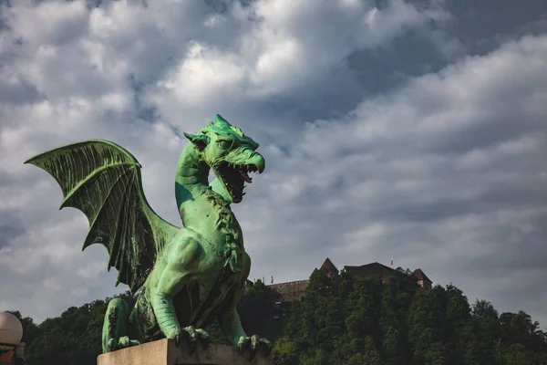 A green dragon statue surrounded by trees under a cloudy sky