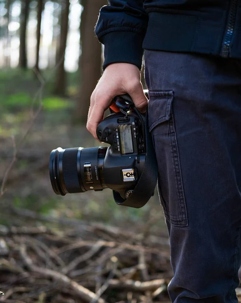 プロのブラックカメラと森の中でそれを保持する写真家の垂直選択焦点 — ストック写真