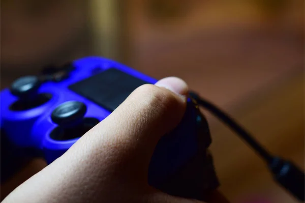 青いビデオゲームコントローラーを押す若い男の子の手 — ストック写真