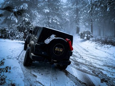 Riverside, ABD 'nin karla kaplı yollarında siyah bir Jeep Wrangler' ın off-road görüntüsü.