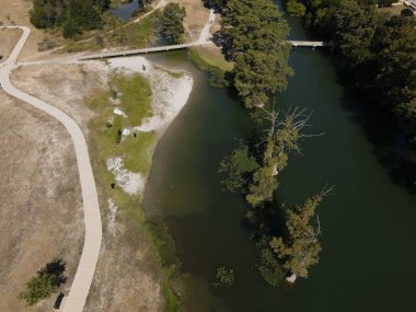 Nehrin yukarısındaki bir köprünün yeşilliklerle kaplı kıyılarından akan bir görüntüsü.
