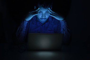 Şirket çalışanı laptopta geç saatlere kadar çalışırken yorgun ve başı ağrıyor