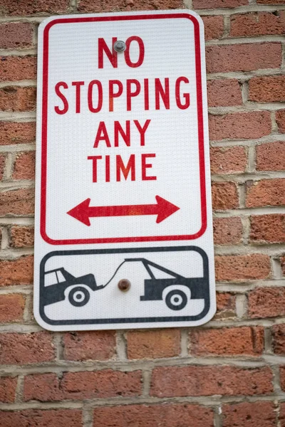 A no parking any time sign on a wall