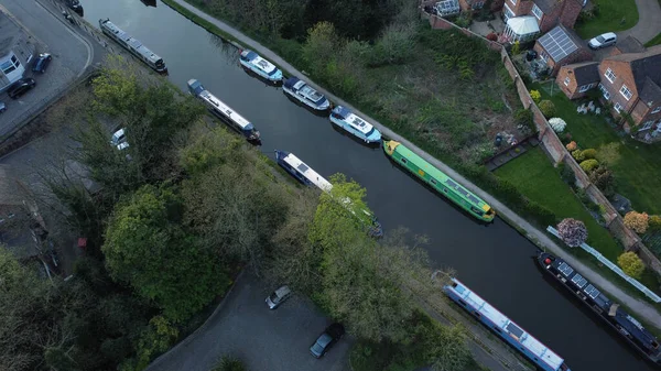 A bird's eye view of boats moored in a river in a small town with green tree