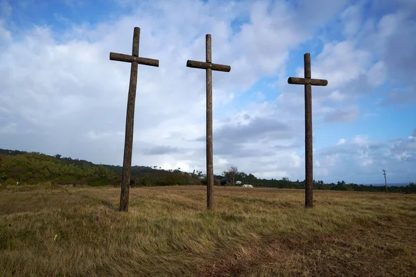 A low angle of three wooden crosses in the field against blue sky background