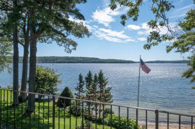 Ağaçlı bir bahçeden güzel bir göl manzarası ve Birleşik Devletler bayrağı.