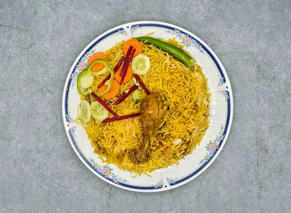 A top view of rice with turmeric with chicken leg and vegetables