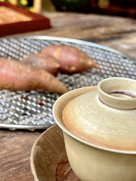 サツマイモを背景にした土のカップの中のお茶の垂直選択的フォーカスショット — ストック写真