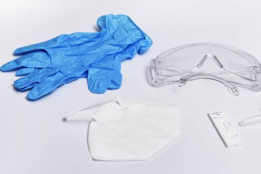 Beyaz arka planda izole edilmiş koruyucu maske, eldiven, gözlük ve ekspres kabartma testi