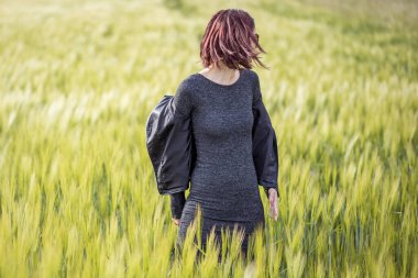 Güneşli bir günde tarlada uzun yeşil çimlerin arasında duran beyaz bir kadının güzel bir portresi.