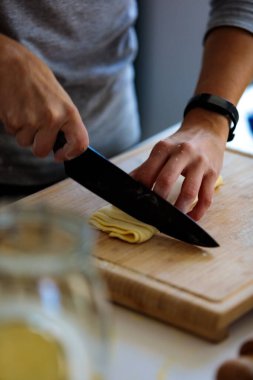 Mutfakta bıçakla hamuru kesen birinin dikey görüntüsü.