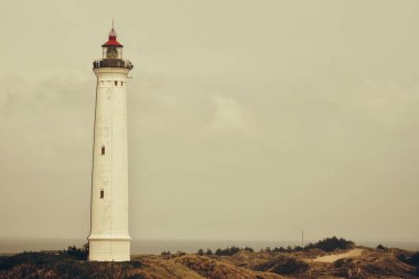 Gri bulutlu gökyüzüne karşı beyaz bir deniz fenerinin güzel bir görüntüsü