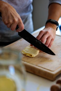 Mutfakta bıçakla hamuru kesen birinin dikey görüntüsü.