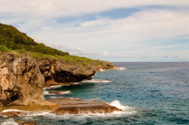 Okyanus dalgalarının güzel manzarası bulutlu bir günde kayalık kıyılara vuruyor.