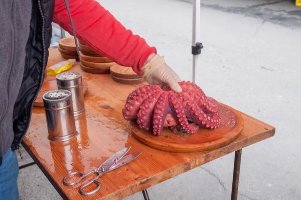 hand of a man holding octopus tentacles cooked in the style of Pulpo a Feira, tradition of galicia. Spain