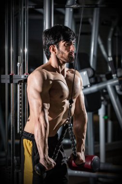 Spor salonunda spor yapan kaslı beyaz bir adamın dikey çekimi.