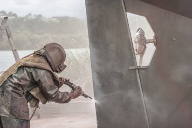 İşçi, yüksek basınçlı kum püskürtme sistemiyle bir yelkenli gemisinin gövdesini kumla kaplıyor.