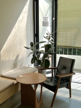 Ofiste küçük yuvarlak bir masa ve deri sandalyeli rahat bir köşenin dikey çekimi.