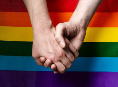 Arka planda LGBT bayrağı olan ellerin yakın plan çekimi