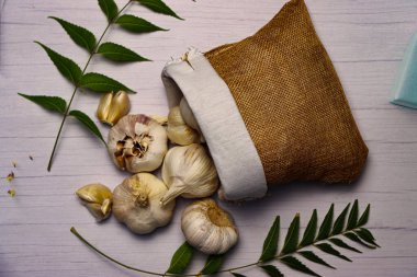 Beyaz ahşap bir masada yaprakları olan sarımsak manzarası.