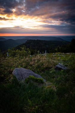 Gün batımında dağların arka planında kayalar olan yeşil alanın dikey görüntüsü.