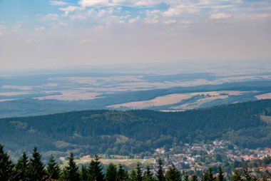 Bulutlu mavi gökyüzünün altındaki ormanlı dağlardan oluşan güzel bir manzaranın hava görüntüsü.