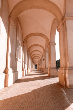 Kemerli bir geçit ve güneş ışığında gölgeli sütunlar.