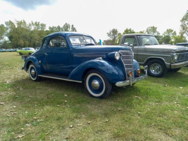 Eski mavi Chevrolet Chevy Master iş coupe 1938 by GM. Yeşil doğa çimleri ve ağaçların arka planı. Klasik araba şovu. Kopyalama alanı
