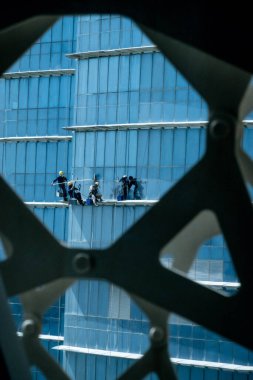 Doha, Katar 'daki kulelerin camlarını temizleyen adamların dikey görüntüsü