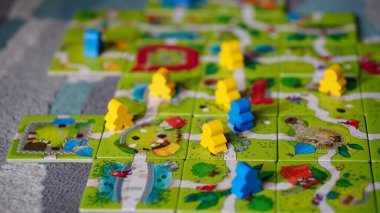 Mindok Carcassonne Junior masa oyununun kartlarından yapılmış bir haritanın üzerinde duran bir heykel.
