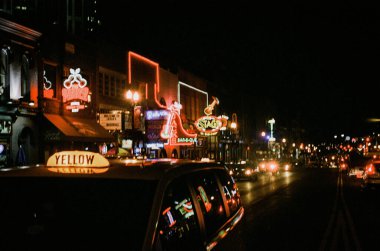 Neon ışıklı bir yolda ilerleyen taksi. Nashville, ABD.
