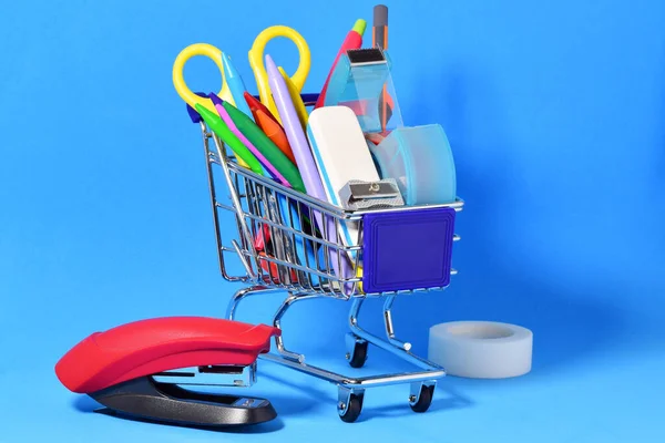 Een Klein Winkelwagentje Met Diverse Schoolbenodigdheden Blauwe Achtergrond — Stockfoto