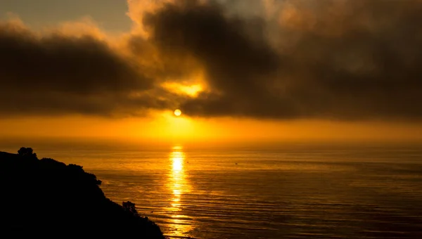 金色的太阳在黑暗的天空中闪烁着 海中反射出光芒 — 图库照片