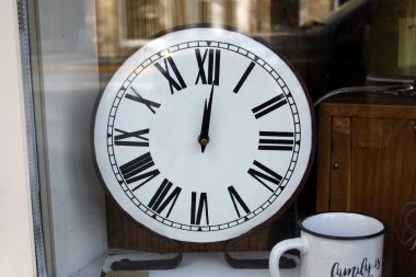 Antika dükkanının vitrininde üzerinde Langley, BC, Kanada 'da bir bardak olan eski beyaz bir saat.