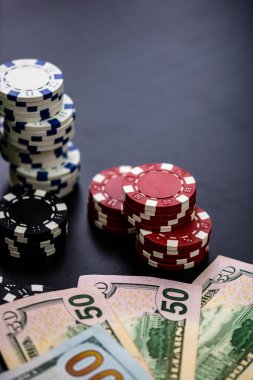 Masadaki para ve kartlarla poker fişlerinin dikey yakın çekimi