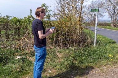 Bir yandan, erkek gözlüklü, ayakta duran ve bir dron kumandası tutan