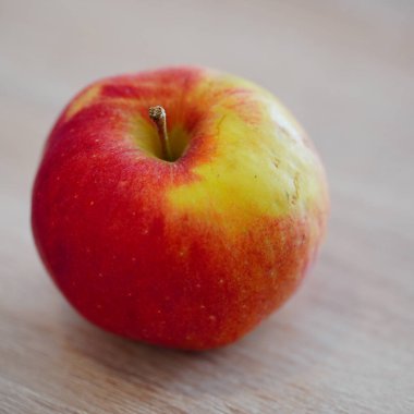 Ahşap bir masada kırmızı ve yeşil bir elmanın yakın plan çekimi.