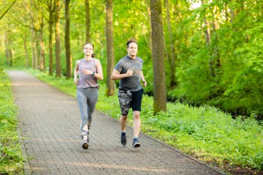 Güneşli bir günde parktaki yürüyüş yolunda koşan beyaz bir çiftin güzel bir fotoğrafı.